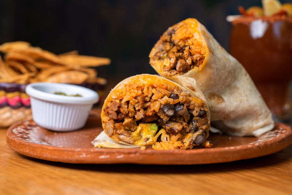 Mouthwatering beef and rice burrito served on a rustic plate with chips.